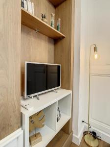 a living room with a tv on a white desk at Appartement de charme: La rochelle/vieux port in La Rochelle