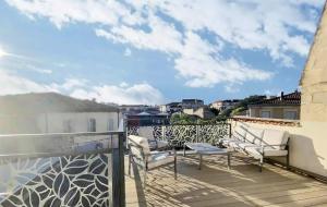 uma varanda com cadeiras brancas e vista para a cidade em Duplex 120m2 terrasse vue sur Nîmes em Nîmes