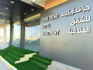 un bâtiment avec un panneau indiquant le grand portail de l'appartement d'hôtel dans l'établissement Grand Orchid Hotel Apartment, à Duqm