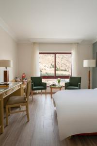 a room with a bed and a desk and chairs at Mövenpick Resort Petra in Wadi Musa