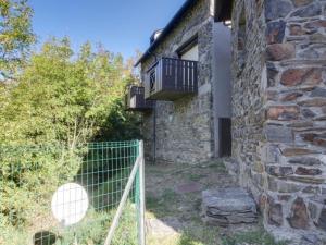 ein Steingebäude mit einem Zaun und einem Balkon in der Unterkunft Appartement T3 Duplex 6 Pers. avec Cheminée et Balcon à Esquièze-Sère - FR-1-402-70 in Esquièze - Sère