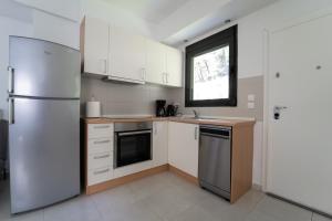 a kitchen with white cabinets and a stainless steel refrigerator at Aetofolia Stella Villas in Fourka
