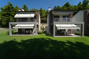 フォルカにあるAetofolia Stella Villasの芝生の上に白傘が2本敷かれた家