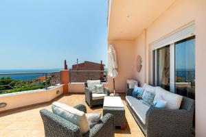 een woonkamer met een bank en stoelen op een balkon bij Villa Serenity a luxury 7 bed villa at Kymi Evia in Paralia Kimis