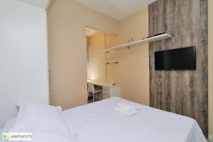 a bedroom with a bed and a tv on a wall at Studio moderno ao lado da praia em Ipanema in Rio de Janeiro