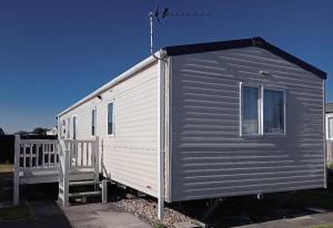 ein graues und weißes winziges Haus mit einer Veranda in der Unterkunft Deluxe 3 Bedroom Caravan with extra en-suite North Shore in Skegness