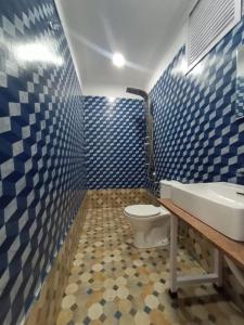 y baño con aseo, lavabo y azulejos azules. en Anthy’s Guesthouse and Restaurant, en Benaulim