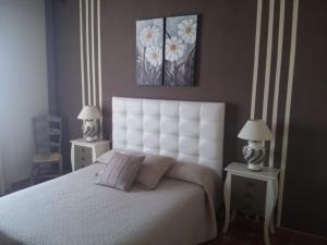 a bedroom with a large white bed with two lamps at Rural Vega de Cazalla in Cazalla de la Sierra