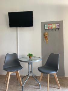 twee stoelen en een tafel met een tv aan de muur bij Guesthouse Anestis in Ángistron
