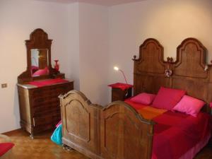 una camera da letto con un grande letto in legno con cuscini rosa di B&B Castellani a Fanna