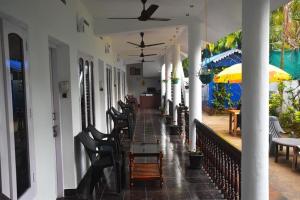 a porch with chairs and a table and an umbrella at Sky Palace Beach Hotel in Trivandrum