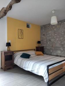 1 dormitorio con cama y pared de piedra en Chambre d'hôtes La terrasse de Sabatas en Chomérac