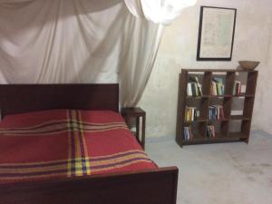 a bedroom with a bed and a book shelf with books at Casa Fabula in Ilha de Moçambique
