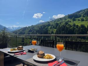 una mesa con dos platos de comida y dos vasos de zumo de naranja en Apartment Allegra, en Küblis