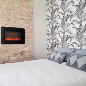 a bedroom with a white bed with a fireplace at Studio calme-équipements haut de gamme in Sarreguemines