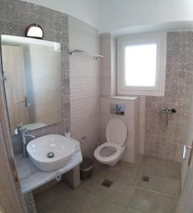 La salle de bains est pourvue d'un lavabo, de toilettes et d'une fenêtre. dans l'établissement Zeus Hotel, à Iraion