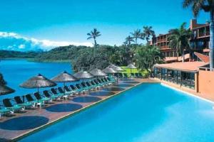 ein Resortpool mit Sonnenschirmen und Wasser in der Unterkunft 2 Bedroom Lagoon Villa Sanlameer Estate, with water tank & UPS in Marina Beach