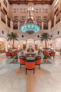 a large lobby with tables and chairs and a chandelier at Mövenpick Resort Petra in Wadi Musa