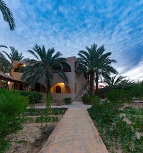 une maison avec des palmiers devant elle dans l'établissement Seliyaa Siwa Inn Hotel, à Siwa
