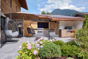 een patio met een parasol en stoelen en een keuken bij Sunshine Apartment Spirit of Deer in Garmisch-Partenkirchen