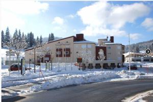 un gran edificio con nieve en el suelo junto a una calle en La Serre - Centre du village - Départ des pistes de fond et Skibus à 50m, en Prémanon