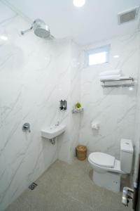 La salle de bains blanche est pourvue de toilettes et d'un lavabo. dans l'établissement Oki Taru Residence, à Kuta