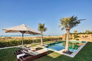 a pool with chairs and an umbrella and palm trees at Rixos Premium Saadiyat Island - All Inclusive in Abu Dhabi