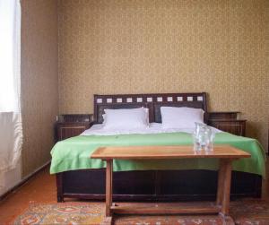 a bed with a green blanket and a wooden table at B&B Sunrise House Aygavan in Aygavan