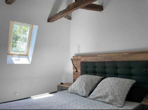 a bedroom with a green headboard and a window at Villa avec jaccuzi in Noailhac