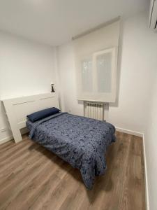 a white bedroom with a bed and a window at Piso centro de valdemoro in Valdemoro