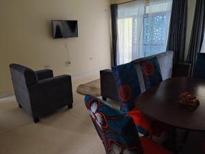 uma sala de estar com uma mesa e cadeiras e uma televisão em Vee's Villa em Kilifi