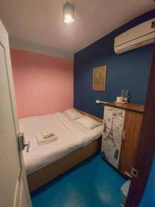 a small bed in a room with a blue wall at D​ Luck​ Hostel in Kanchanaburi City