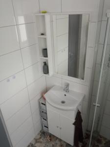 a white bathroom with a sink and a mirror at Kiss-Szőllősi Vendégház II-RAMI in Debrecen