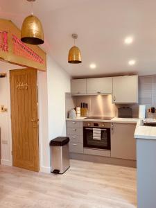 a kitchen with stainless steel appliances and gold pendant lights at SHINE CHALET - UNIQUE & COMFORTABLE ACCOMMODATION in Redruth