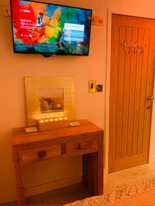 a room with a table with a television on the wall at SHINE CHALET - UNIQUE & COMFORTABLE ACCOMMODATION in Redruth