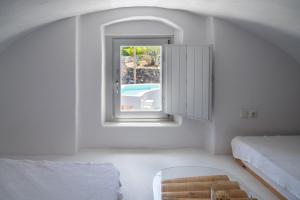 a room with a window and a bed and a chair at Karpimo Suites in Éxo Goniá