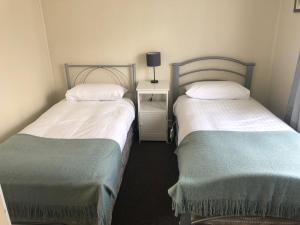 two twin beds in a room with a table at Maydena Chalet in Maydena