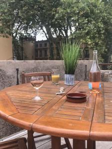 una mesa de madera con 2 copas y una botella de vino en Au coeur de ville avec terrasse, en Céret