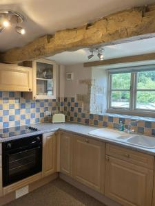 a kitchen with wooden cabinets and a sink and a window at Honey Cottage, Halford (Annex cottage) in Halford