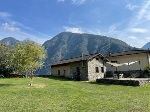 ein Steinhaus mit einem großen Hof mit einem Berg in der Unterkunft Rustico a Roveredo GR in Roveredo