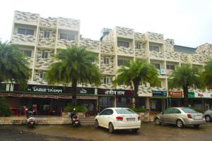 a large building with cars parked in a parking lot at Le Jardin Resort and Spa in Karjat