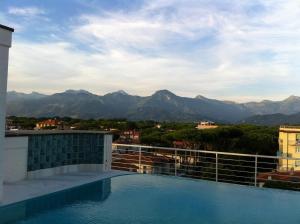 a swimming pool on top of a building with mountains at Hotel Bracciotti in Lido di Camaiore