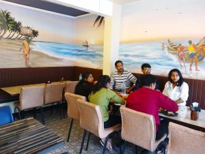 un grupo de personas sentadas en mesas en un restaurante en Le Jardin Resort and Spa, en Karjat