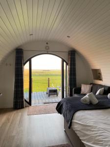 Millview Meadow Retreats في غريت يورماوث: غرفة نوم بسرير كبير واطلالة على فناء