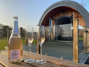 Millview Meadow Retreats في غريت يورماوث: كأسين من النبيذ الأبيض على طاولة خشبية
