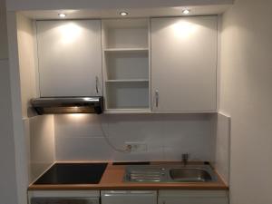a kitchen with white cabinets and a sink at City Center Apartment in Munich