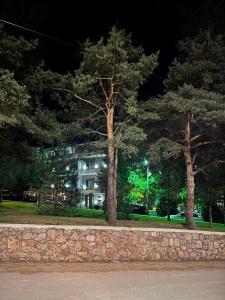 un bâtiment de nuit avec des arbres devant lui dans l'établissement Dim's Hotel & Restaurant, à Korçë