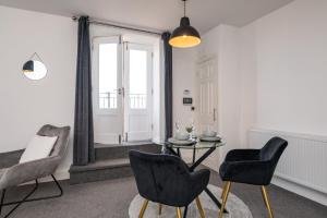 uma sala de estar com uma mesa e duas cadeiras em The Croston balcony apartment- located on the central promenade, beach front and sea views em Morecambe