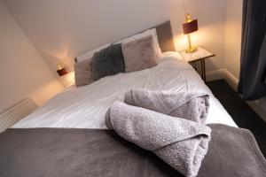 a white bed with two pillows and towels on it at The Croston balcony apartment- located on the central promenade, beach front and sea views in Morecambe