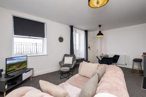 a living room with a couch and a tv at The Croston promenade balcony apartment- Morecambe central promenade, beach front and sea views in Morecambe